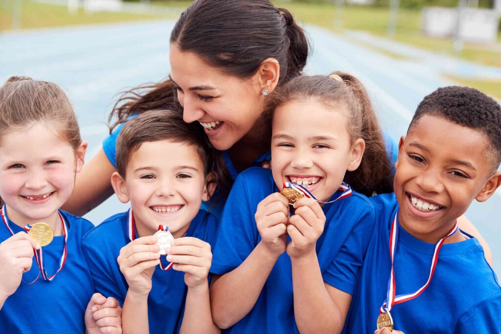 A woman and four kids smiling and holding medals